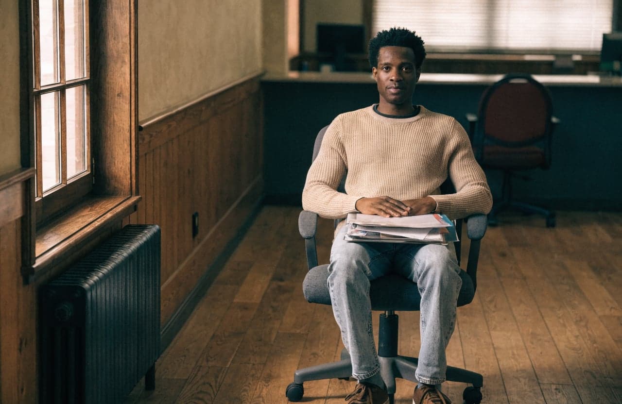 Man seated in an office waiting area holding a folder of documents before a meeting
