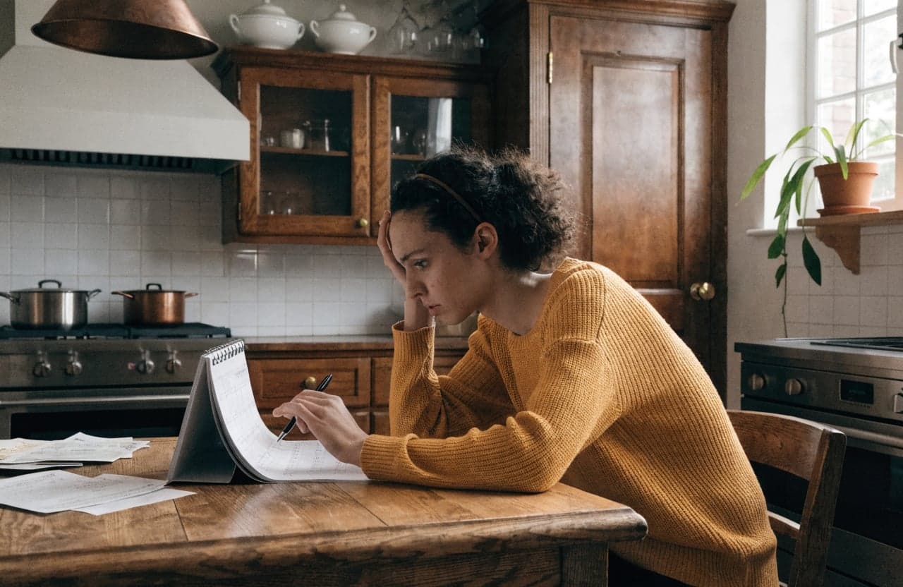 Worker tracking payment dates in a notebook at a kitchen table